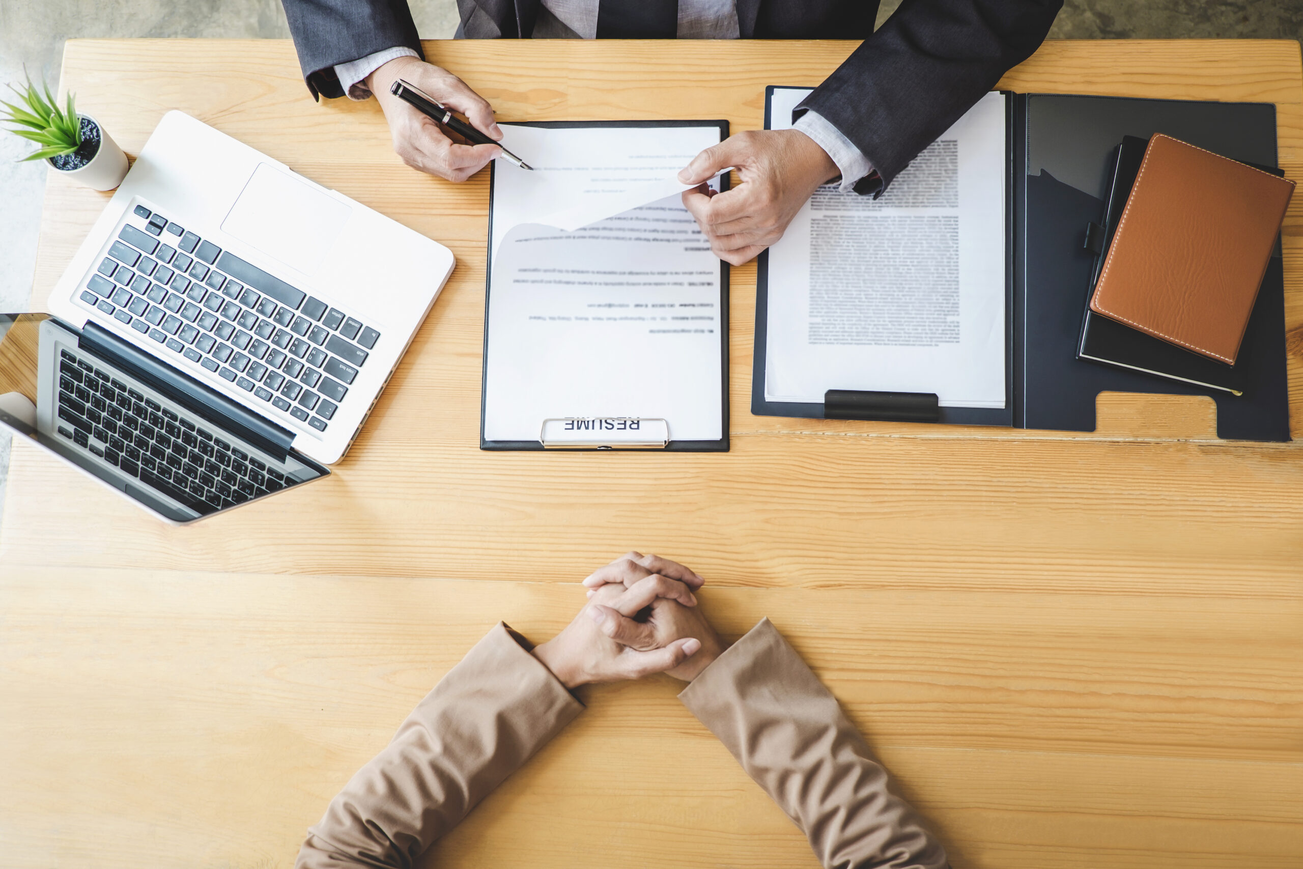 top view of 2 people seated on a table and HR manager is looking at applicant resume